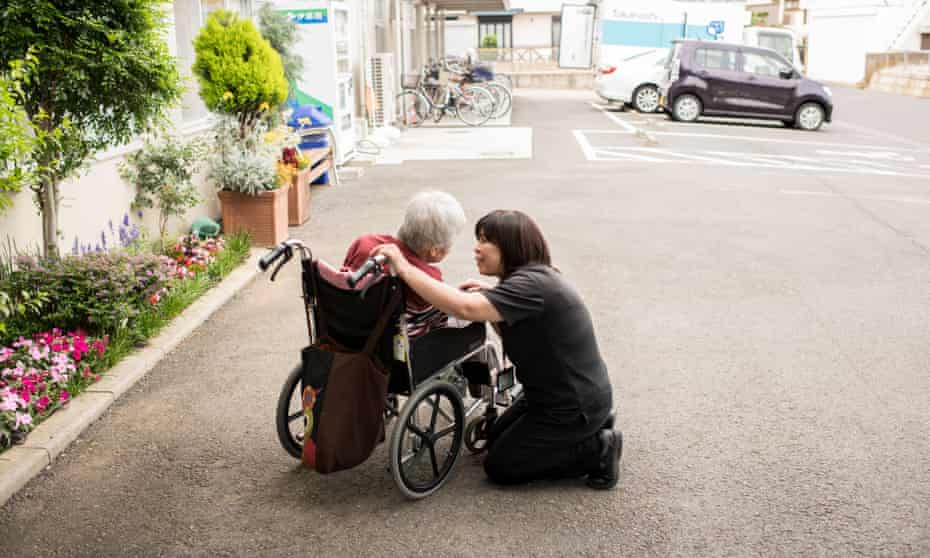a member of staff at a dementia day centre in japan speaks to a customer