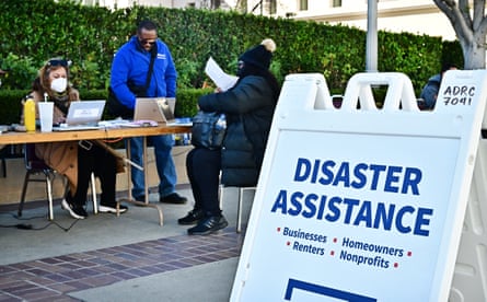 People sitting at a table with a sign in the front reading ‘Disaster Assistance’.