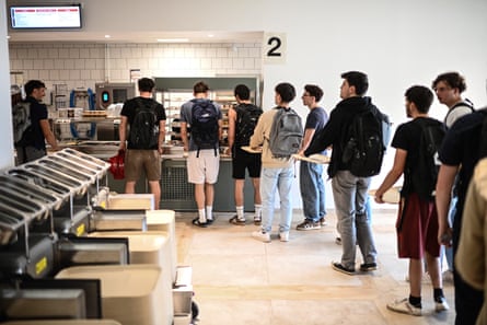 Students carry trays while waiting in a queue to be served at a food counter