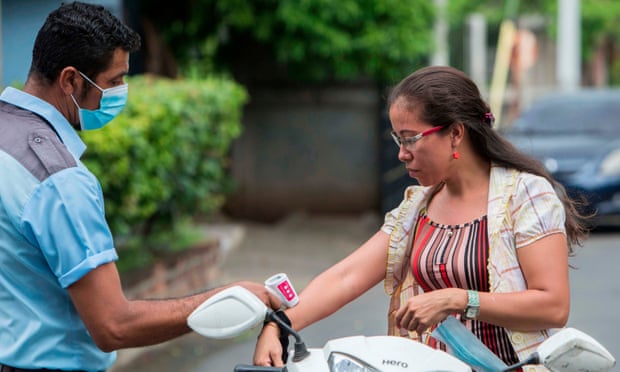 A health worker measures a woman’s temperature at the entrance of Managua Cathedral in Managua, Nicaragua.