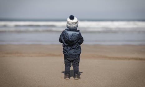 Little boy looking at the sea on a sandy beach