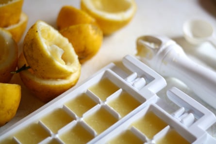 Half lemon with lemon juice in ice-cube containers.