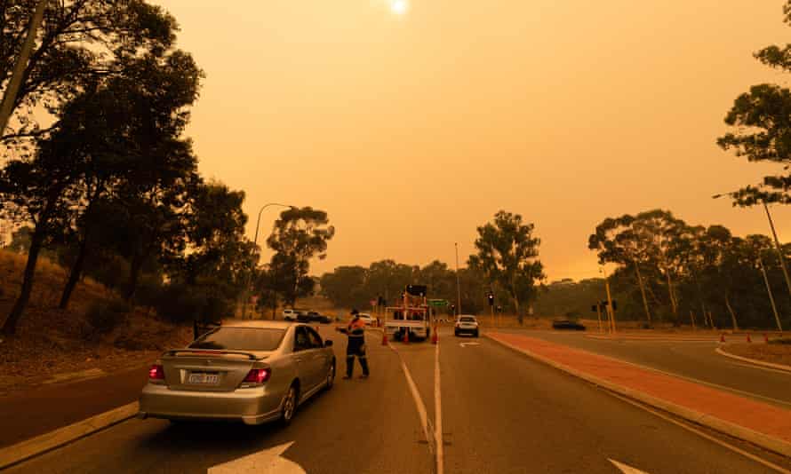 Vehicles are diverted around a road block on Great Northern Highway in Perth on Tuesday as an out-of-control bushfire raged in the Perth Hills.