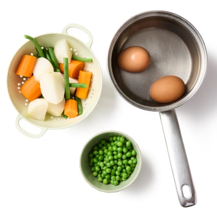 A pan with eggs in it, a bowl of peas and a mix of vegetables in a colander