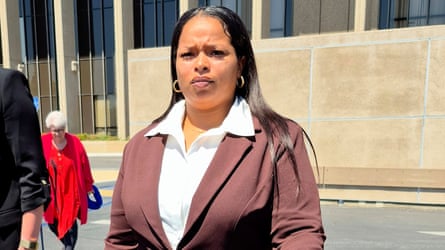 woman in white shirt and maroon blazer stands outside