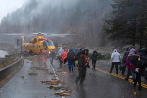 Crew members from Royal Canadian Air Force 442 Squadron lead some of over 300 motorists stranded by mudslides towards a CH-149 Cormorant helicopter for their evacuation, in Agassiz