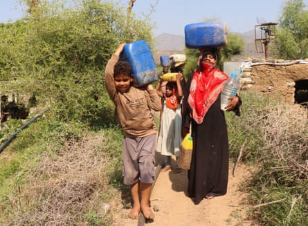 People carry jerry cans as they collect water for a makeshift camp