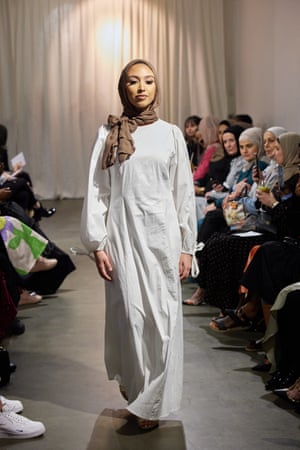 A model wearing a headscarf and long white gown walks the modest fashion runway