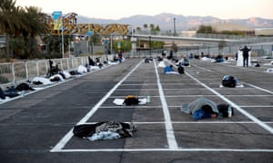 Homeless people sleep in a parking lot with spaces marked for social distancing in Las Vegas.