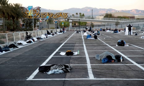 Homeless people sleep in a parking lot with spaces marked for social distancing in Las Vegas.