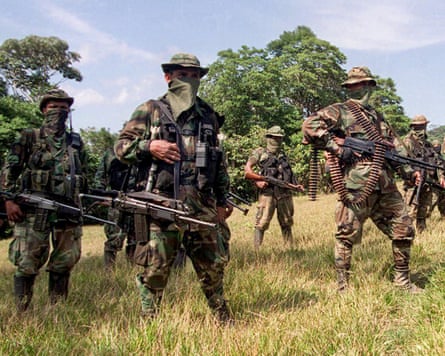 Masked and heavily armed men in combat gear standing in formation in a field