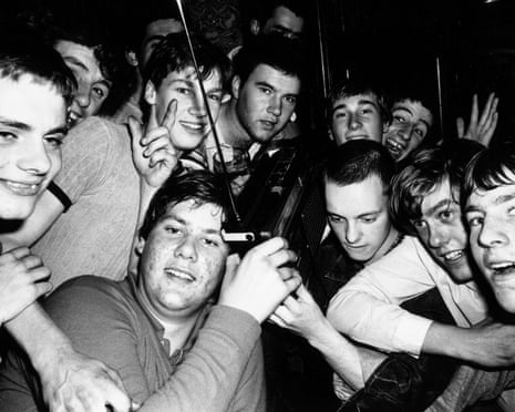 A group of football fans listen to a portable radio in October 1980.