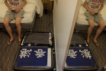 An asylum seeker from Hong Kong sitting on a bed in a hotel room
