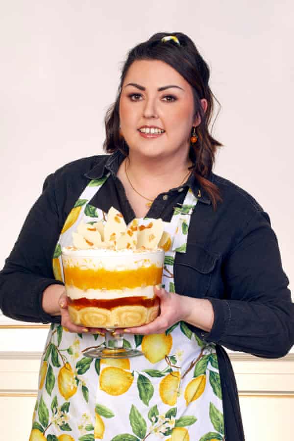 Jemma Melvin in an apron smiling and holding a bowl of her lemon trifle