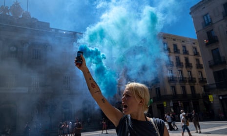 A climate activist at in Barcelona is seen with a blue smoke flare during a rally