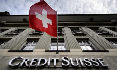 Swiss flag flies over a sign of Swiss bank Credit Suisse