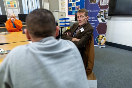 Two men in conversation sitting at a table with books on