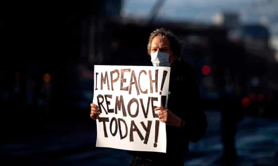 Protester Kenneth Lundgreen holds up a sign calling for the impeachment of President Donald Trump as police put together barricades outside Twitter corporate headquarters in San Francisco, California.