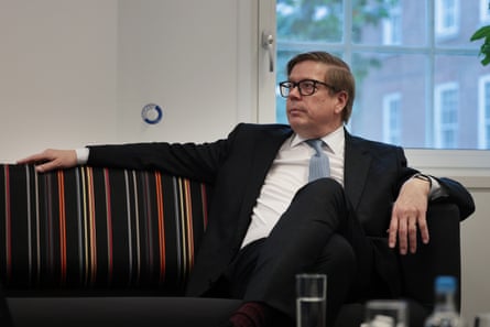 EU ambassador to UK Jukka Salovaara in dark suit and tie on striped sofa.