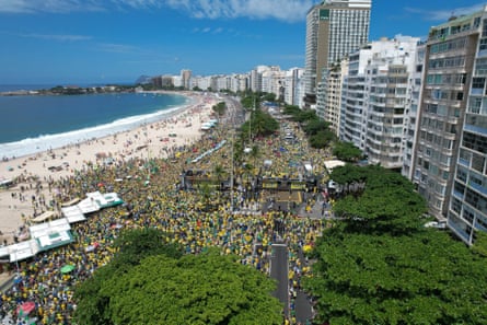 Aerial view of a crowd of people, many in yellow shirts, on a beachfront lined with high-rise buildings