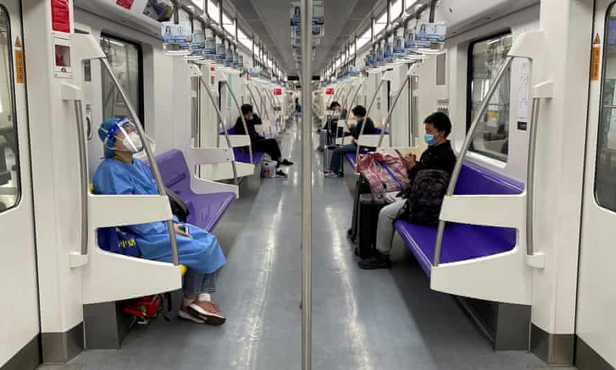 A passenger in a protective suit rides on a train as some lines resumed