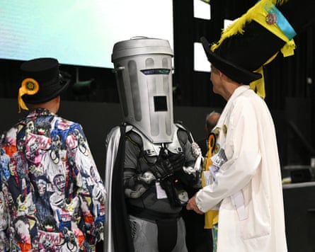 Count Binface chats to two men wearing top hats and colourful outfits
