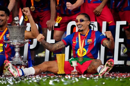 Raphinha sits on the pitch next to the Spanish Super Cup