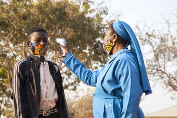 A teacher reads temperatures at a school in Lusaka, Zambia. Research suggests the nation’s death toll may be under-reported tenfold.