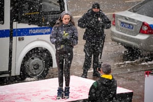 A woman poses on a podium installed on International Women’s Day in the city centre, with a police officer in the background. International Women’s Day on 8 March is an official holiday in Russia, where men give flowers and gifts to female relatives, friends and colleagues