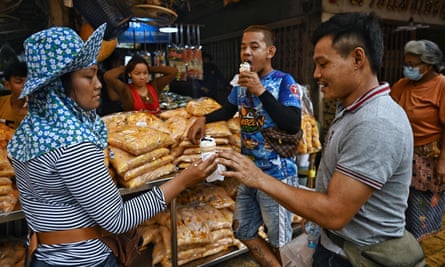 An ice-cream seller handing a man an ice-cream cone