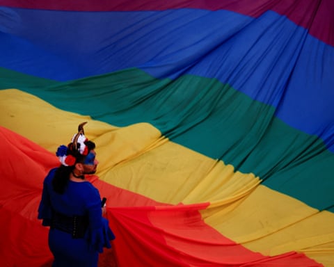 A Malta Pride participant carries a giant rainbow flag