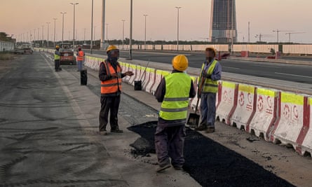 Workers on a road with a half-built tower in the background