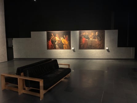 Interior of a museum with a bench and paintings in background.