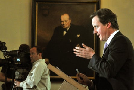 David Cameron speaking in front of a portrait of Winston Churchill