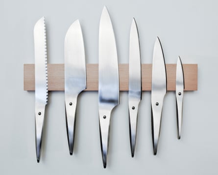Steel kitchen knives on a wooden, magnetic wall rack.