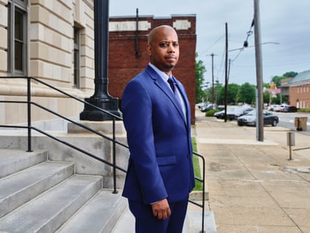 a man in a blue suit poses for a photograph on the steps of a building