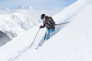 Skier Skiing DownhillFemale skier skiing donhill in front of a beautiful mountain range