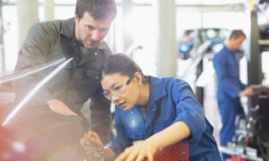 Mechanics working on engine in auto repair shop.