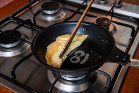 Someone folds an omelette in a pan with chopsticks.