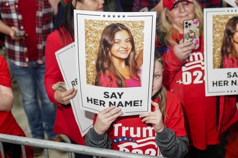 people in red shirts hold up picture of a young woman