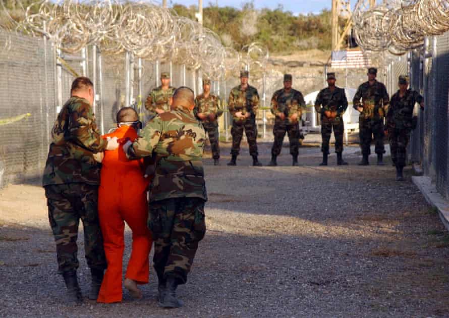 US army military police escort a detainee to his cell in Camp X-Ray on 11 January 2002.