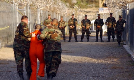 US Army military police escort a detainee to his cell in Camp X-Ray at Guantánamo Bay, Cuba, in 2002