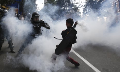A protester charges a police officer with a gas canister before the start of a bullfight in Colombia.
