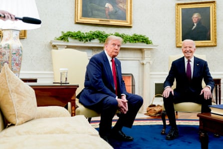 two men sitting on chairs in a room with paintings on the walls