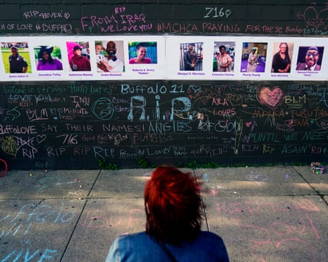 a person looks at wall with photos of victims