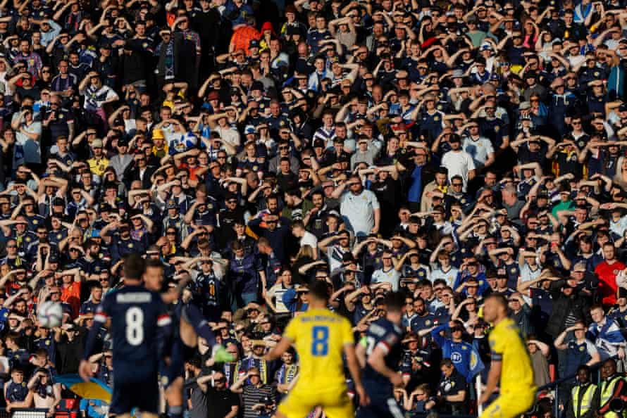 Scotland fans shield their eyes from the sun as they watch the match.