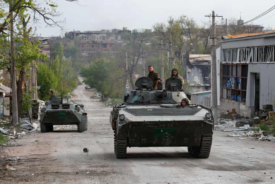 Service members of pro-Russian troops ride an infantry combat vehicle through the streets of Mariupol on Thursday.