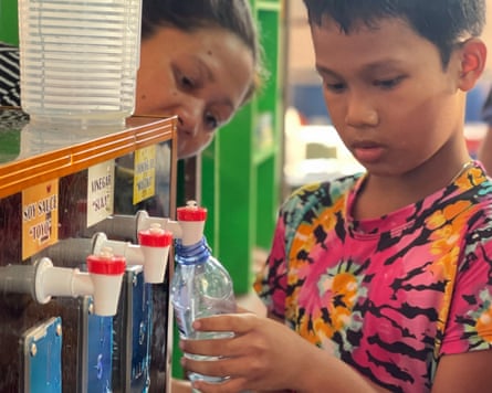 A child fills a bottle from a spout