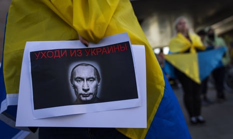 FILE - A demonstrator holds a banner depicting Russian President Vladimir Putin during a pro-Ukraine protest outside the Russian Embassy, after Russian troops have launched their anticipated attack on Ukraine, in Tel Aviv, Israel, Thursday, Feb. 24, 2022. Sign in Russian reads "get out of Ukraine". (AP Photo/Oded Balilty, File)