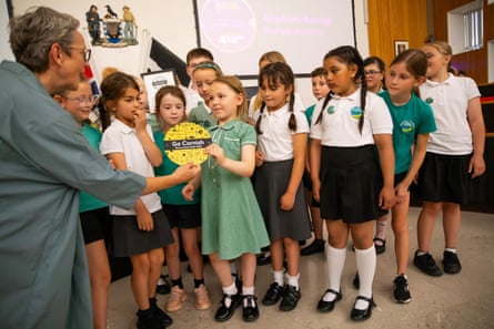 Several schoolchildren at Truro county hall, with one of them accepting a cardboard circle from an adult labelled “Go Cornish”